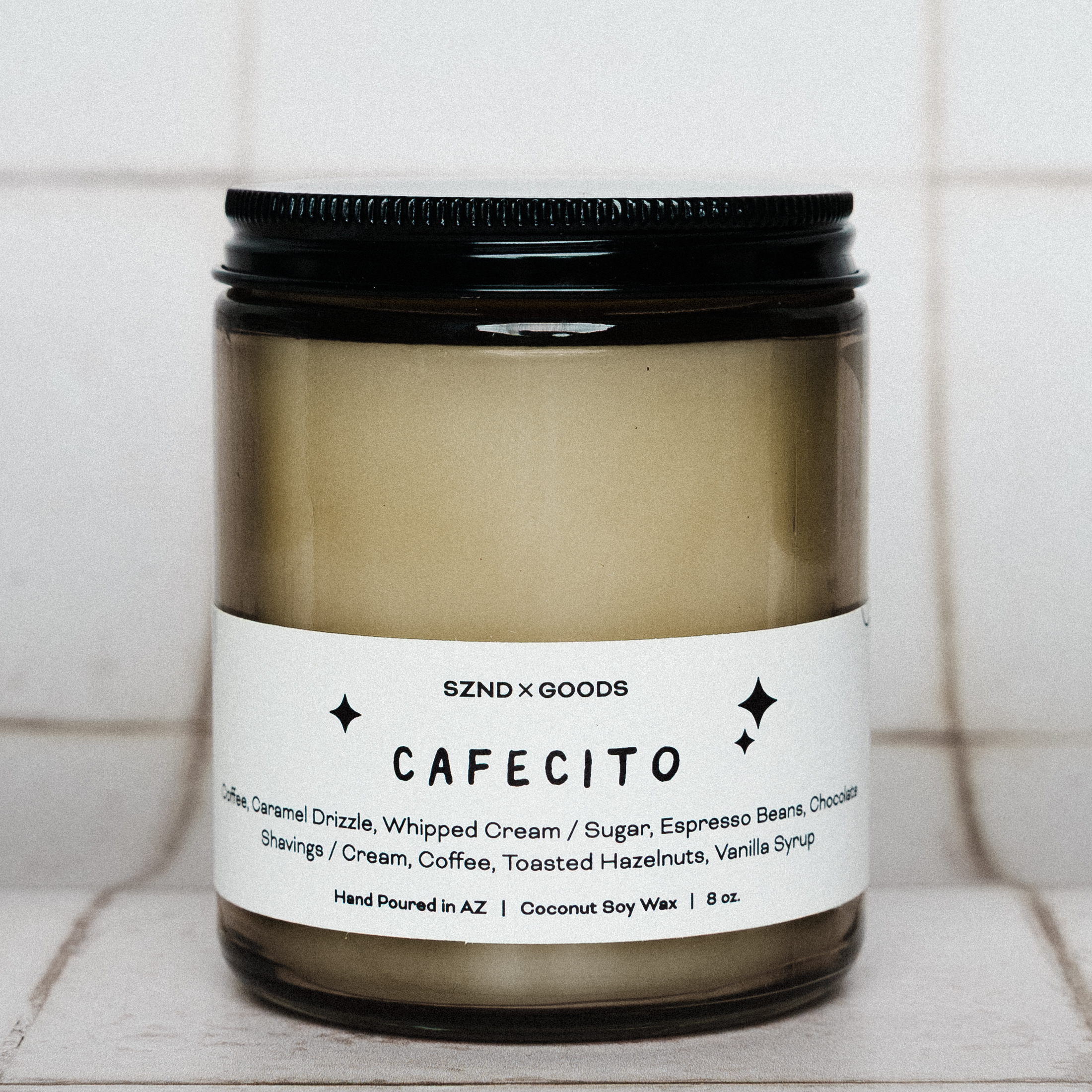 Candle labeled 'CAFECITO' with a black lid on a tiled surface.