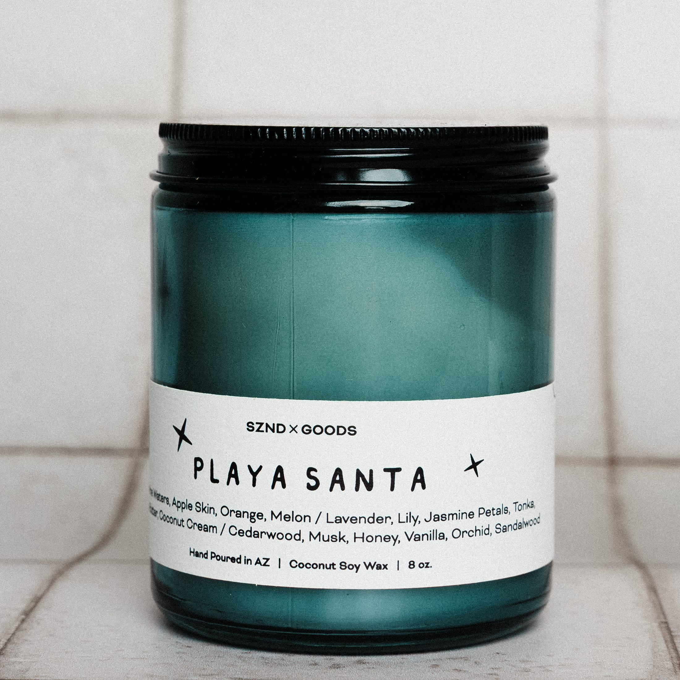 Candle jar labeled 'Playa Santa' on a tiled surface