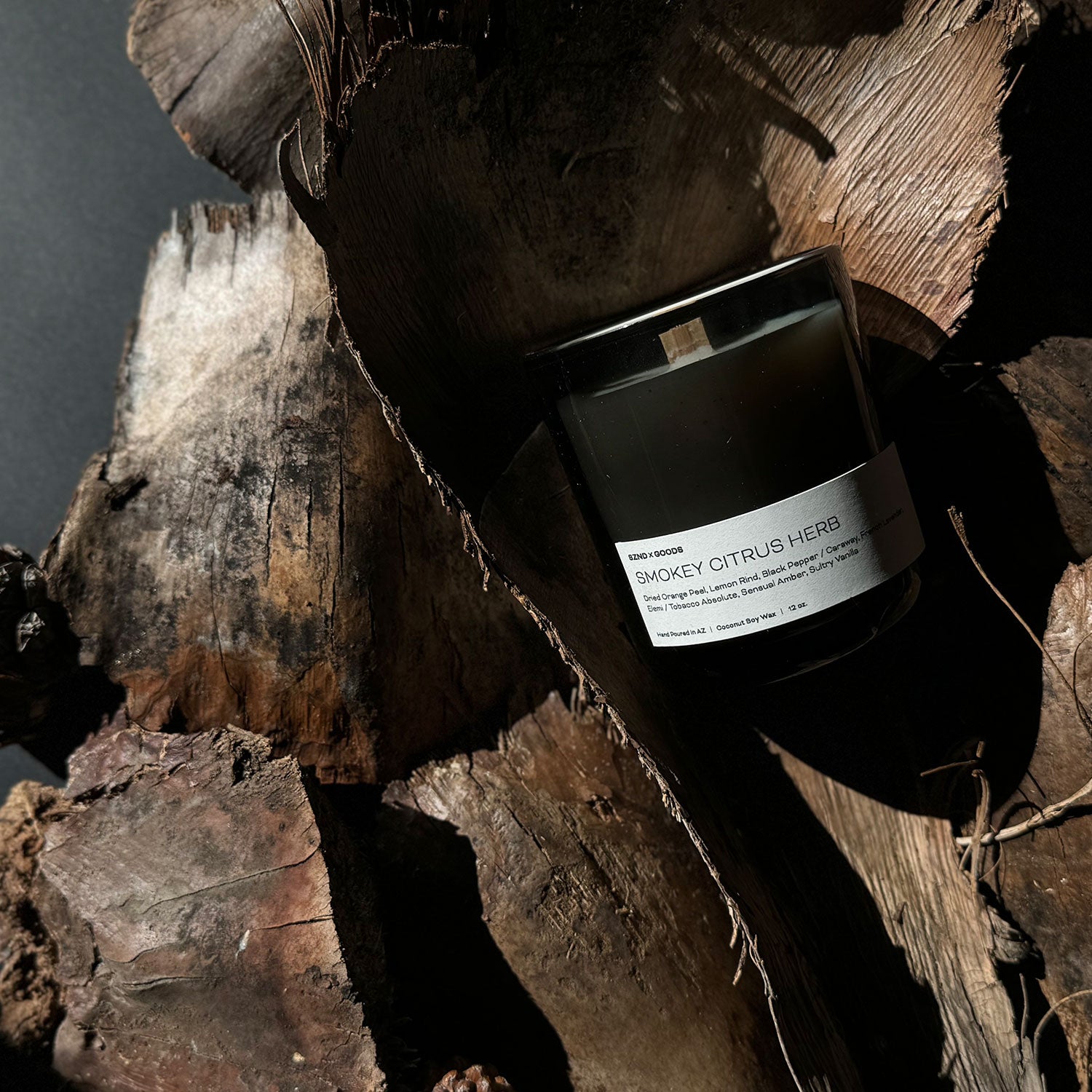 Smokey Citrus Herb candle laying down on a wood piece.