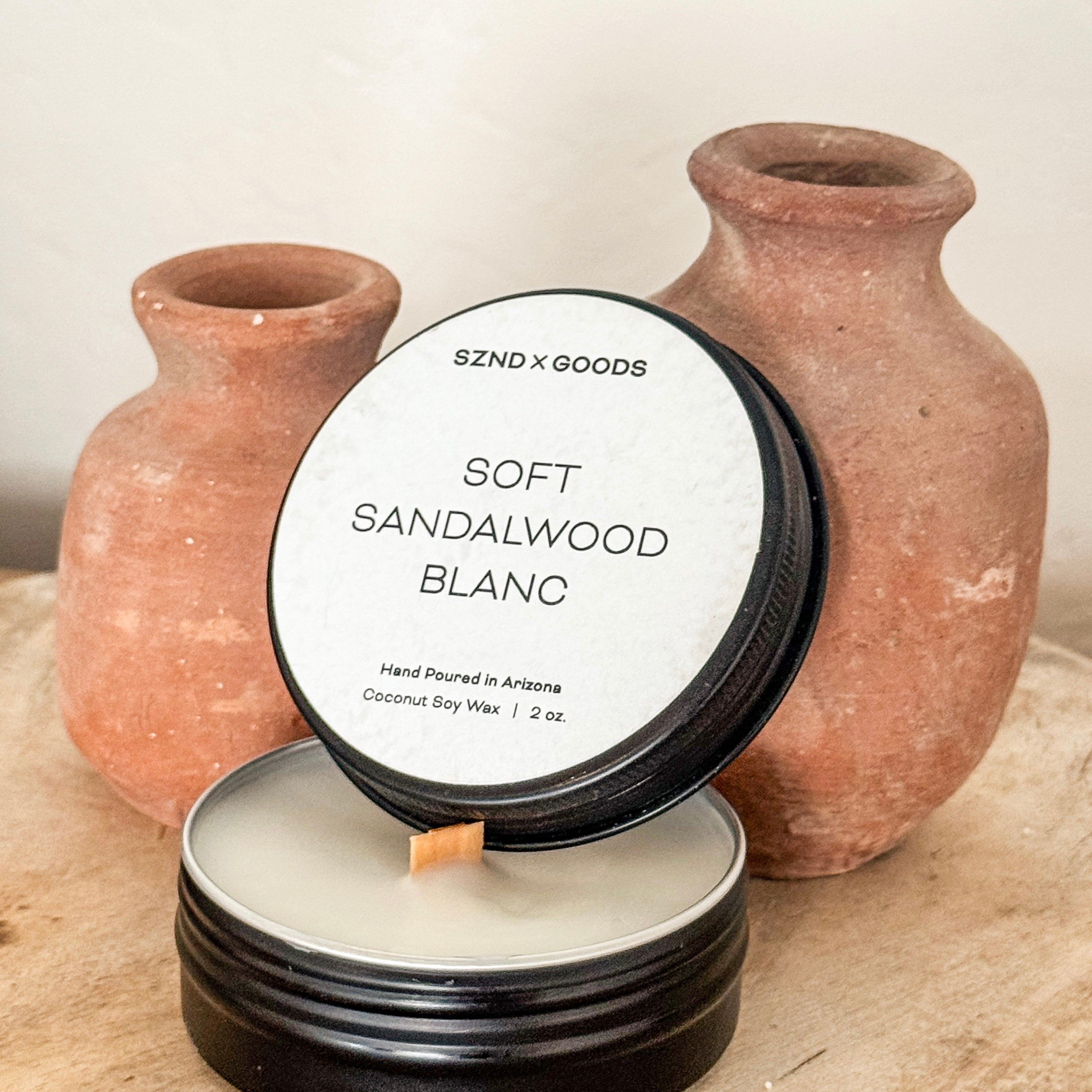 Candle labeled 'Soft Sandalwood Blanc' with two terracotta vases in the background.