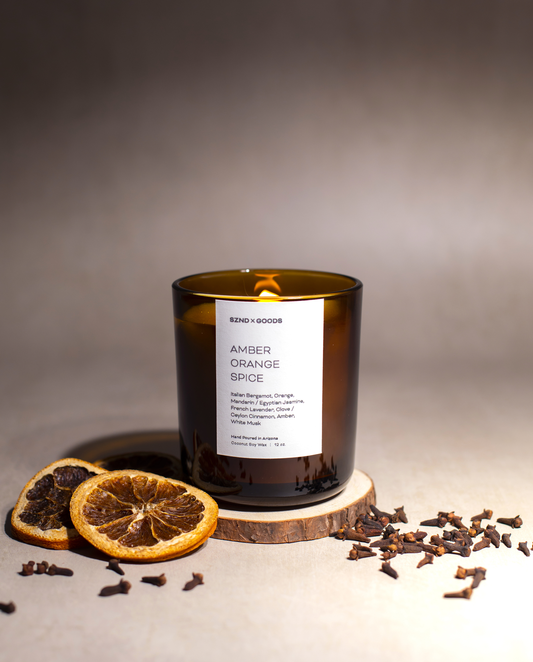 Amber Orange Spice 12oz wooden wick candle with dried oranges and spices around the candle.