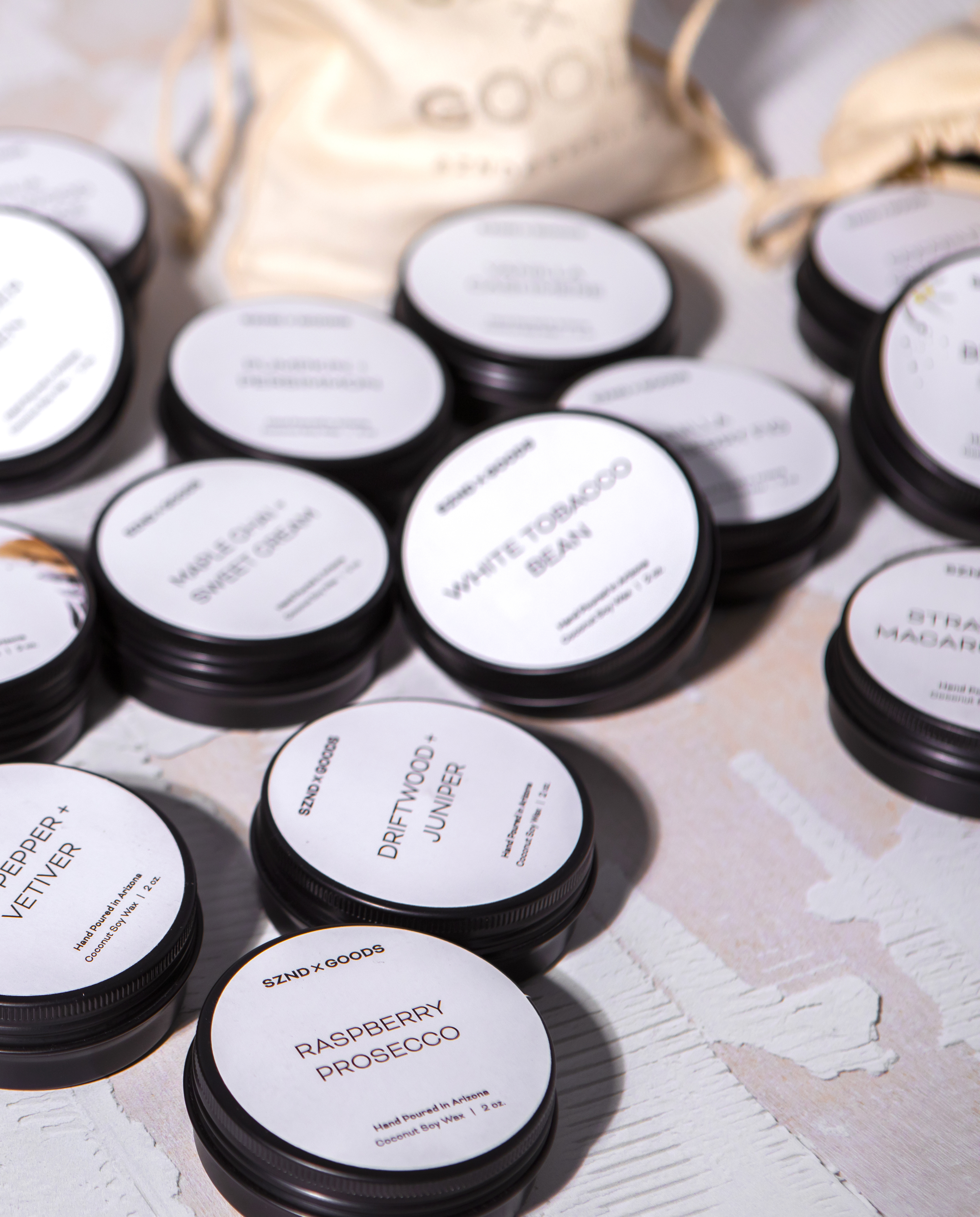 Collection of small mini candles with labeled lids on a textured surface.