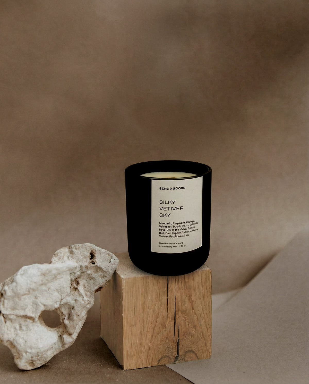 Silky Vetiver Sky candle on a wooden block with a textured background