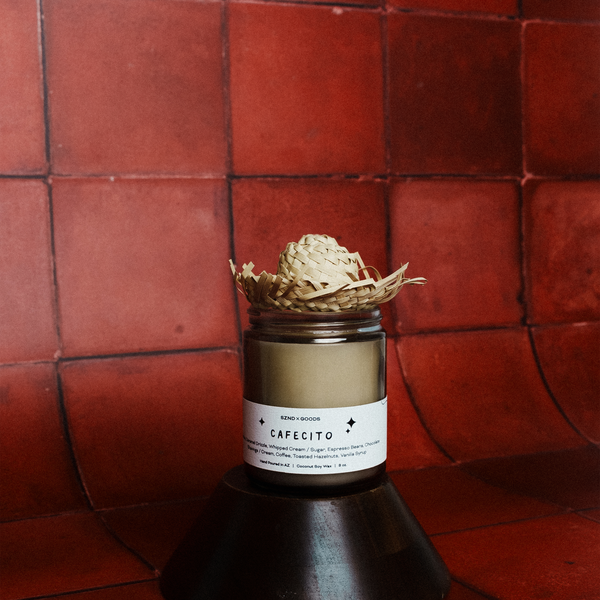 Cafécito candle with decorative elements on a red tiled background