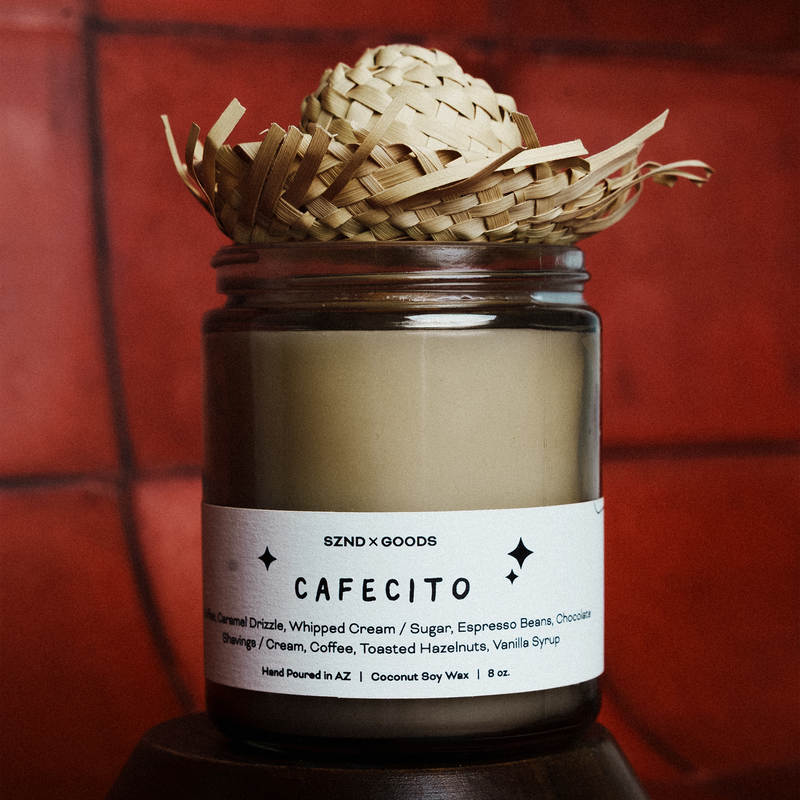 Candle labeled 'CAFECITO' with a wicker basket on top against a red tiled wall.