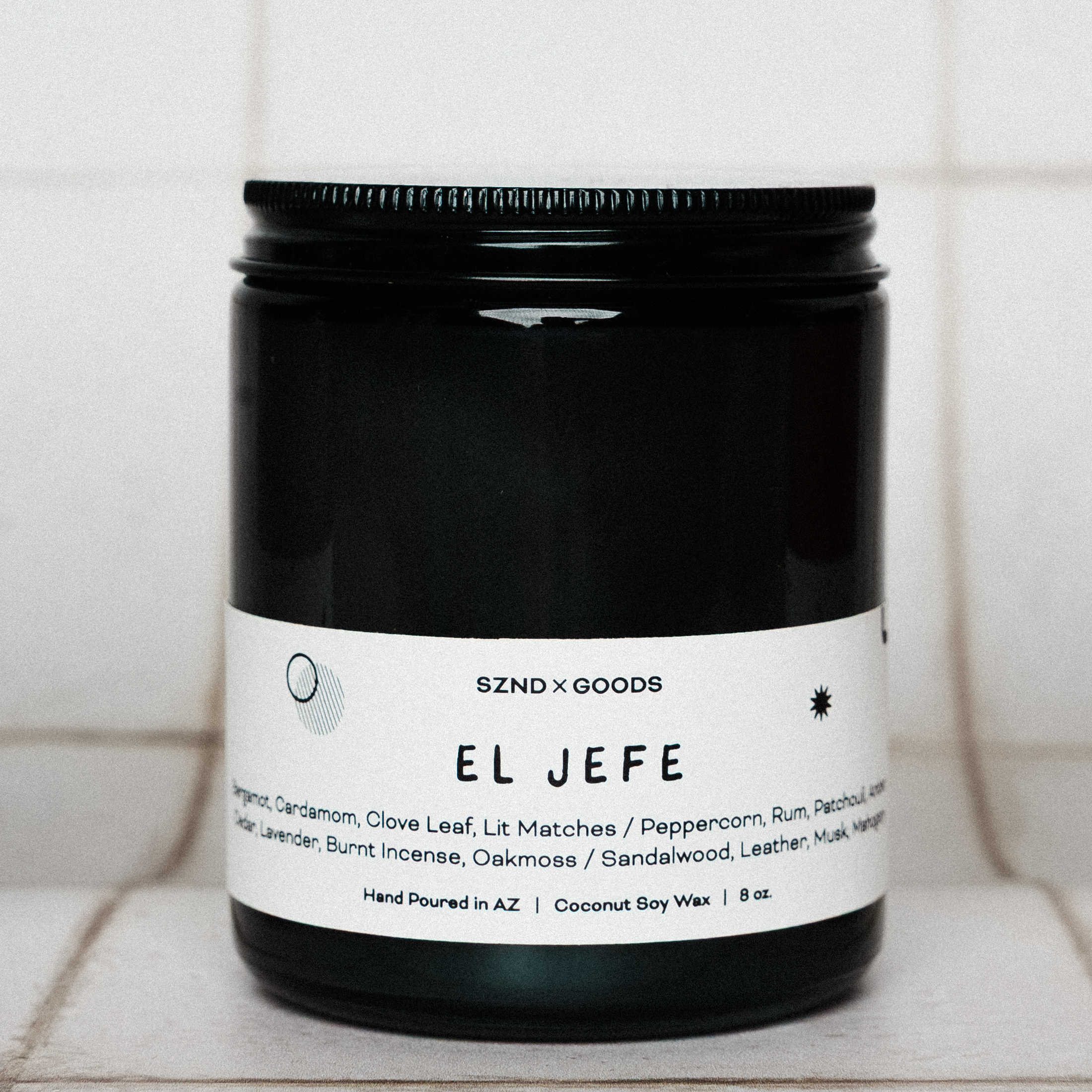 Black candle jar labeled 'EL JEFE' with a white label on a tiled surface