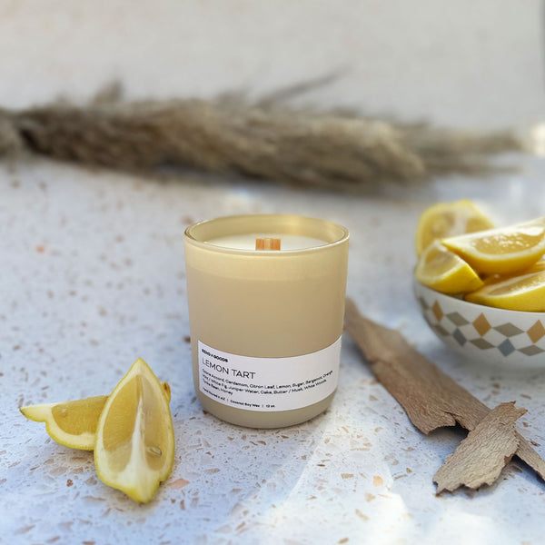 Lemon Tart candle on a white background with lemon and wood props.