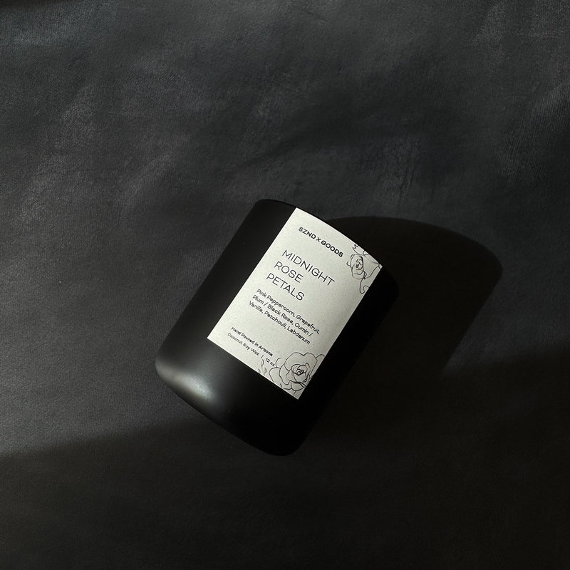 Wooden wick candle in a black vessel on a black background.