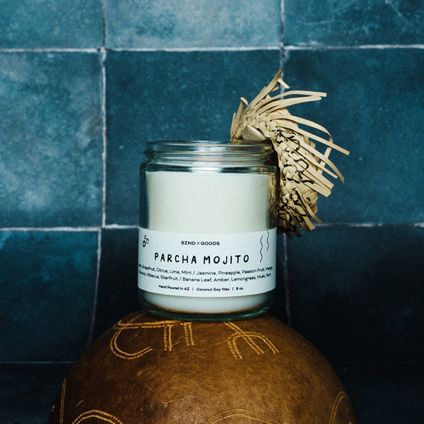 Wooden wick candle labeled 'Parcha Mojito' on a textured surface with a blue tiled background