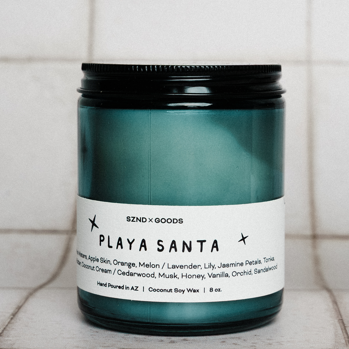 Candle jar labeled 'Playa Santa' on a tiled surface