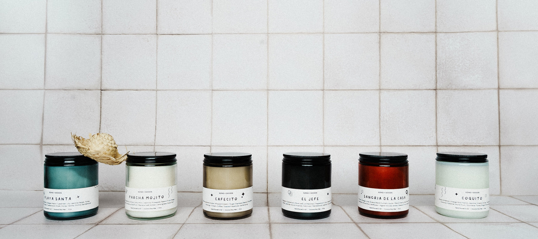 Our Puerto Rican Collection of candles with labels on a tiled wall background.
