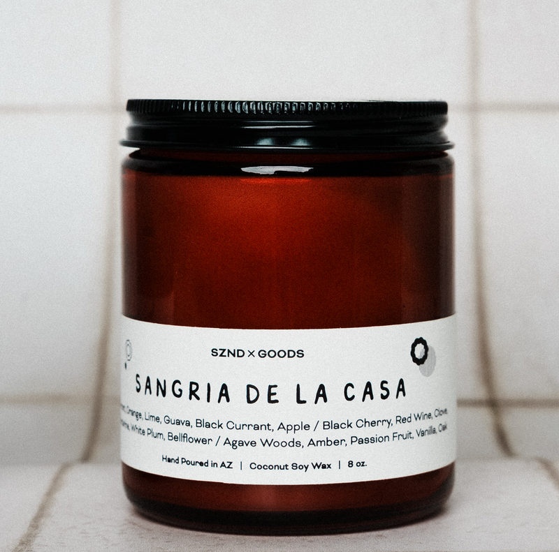 Candle jar labeled 'Sangria de la Casa' by SZND x GOODS on a tiled surface.