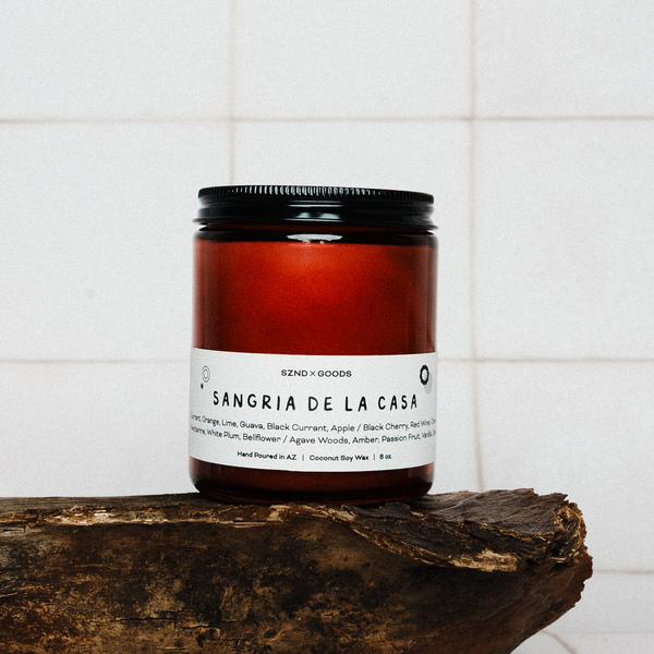 Sangria de la Casa wooden wick candle on a wooden surface with a white tiled background.