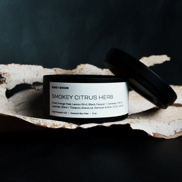 Candle jar with 'Smokey Citrus Herb' label on a dark background