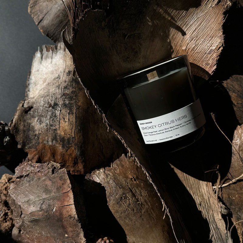 Smokey Citrus Herb candle laying down on a wood piece.