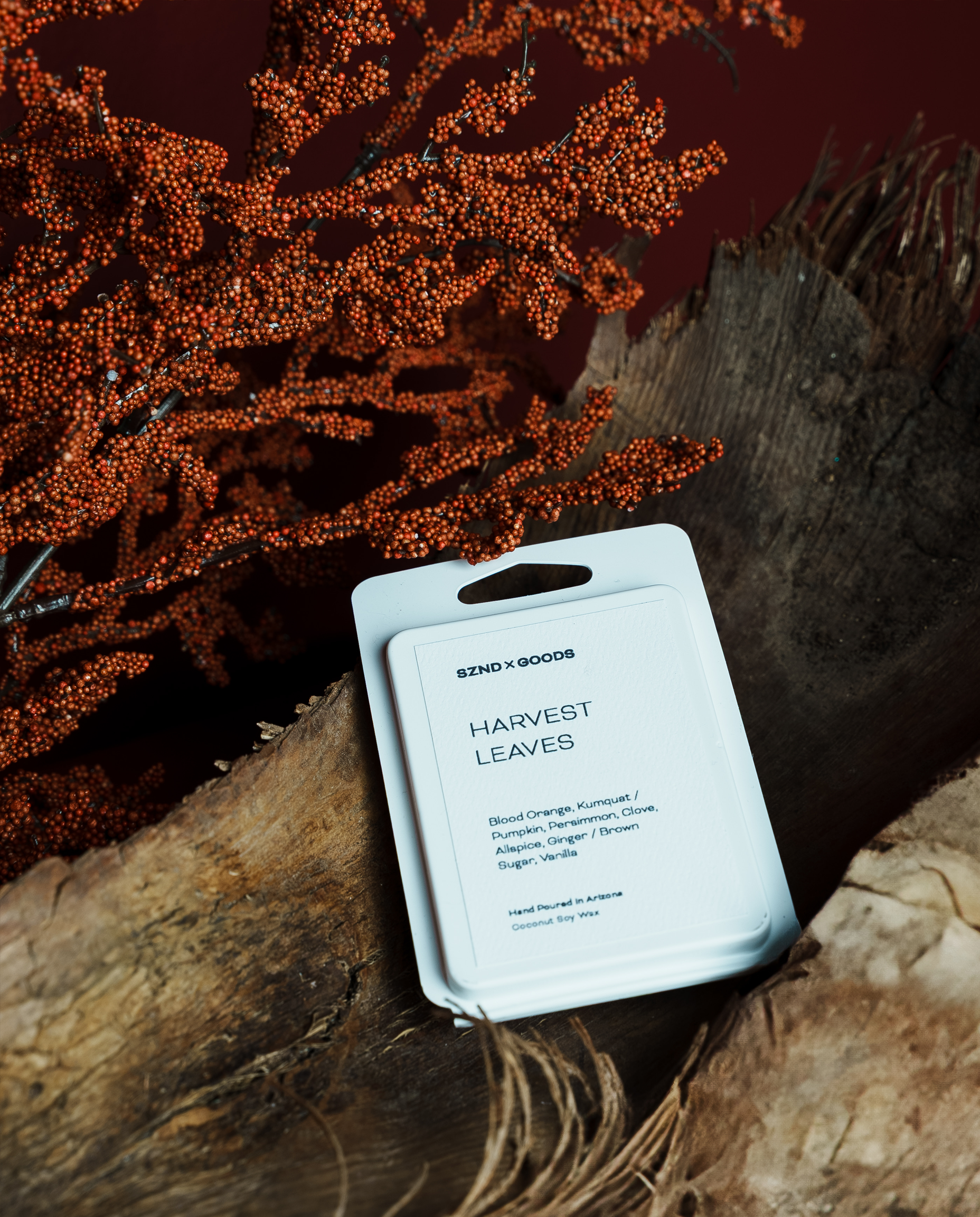 Harvest Leaves wax melt rests on a rustic wood surface with dried orange-brown botanical branches in the background.