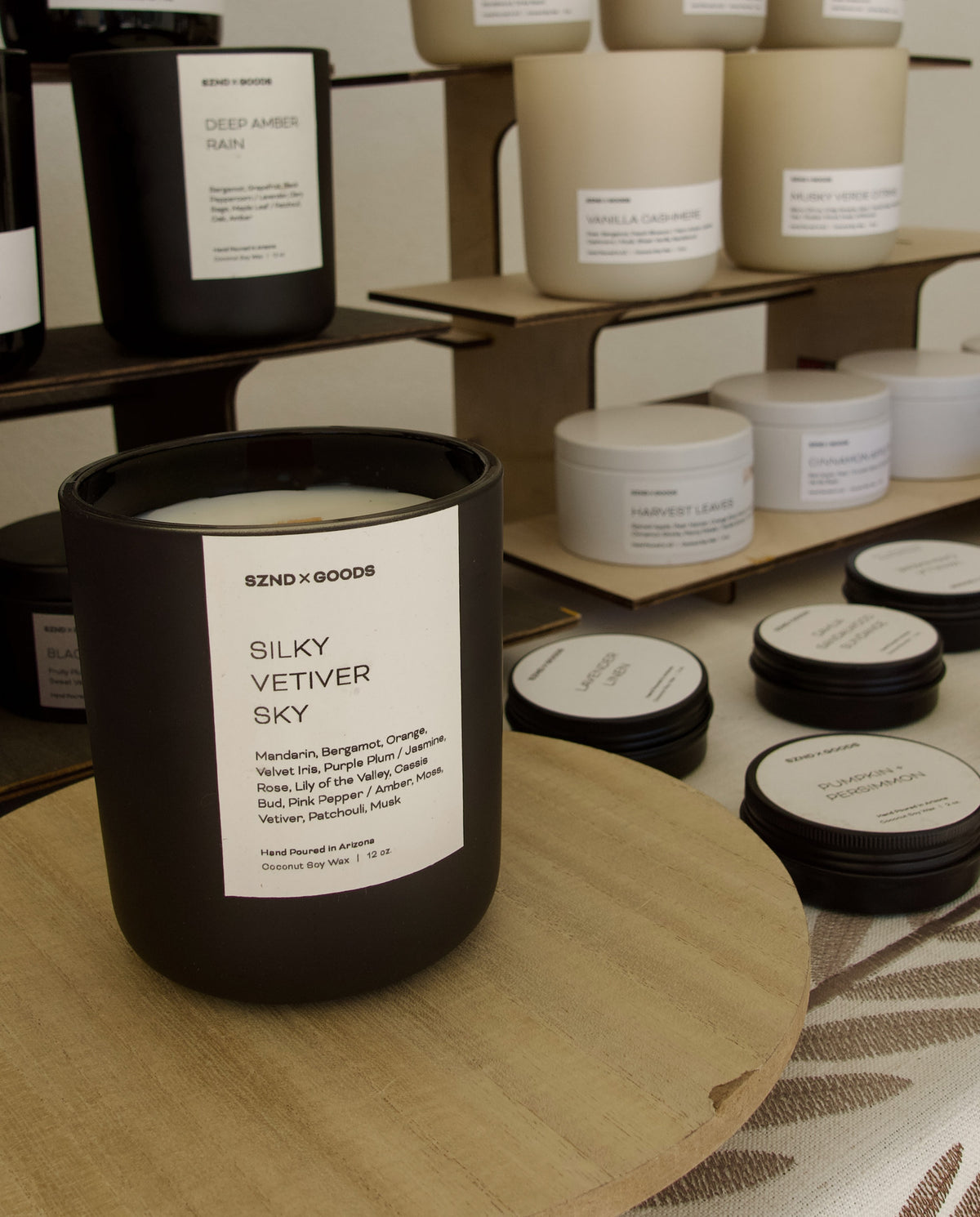 Our Silky Vetiver black candle jar at the forefront of an image with a bunch of our other candle scents in the background.